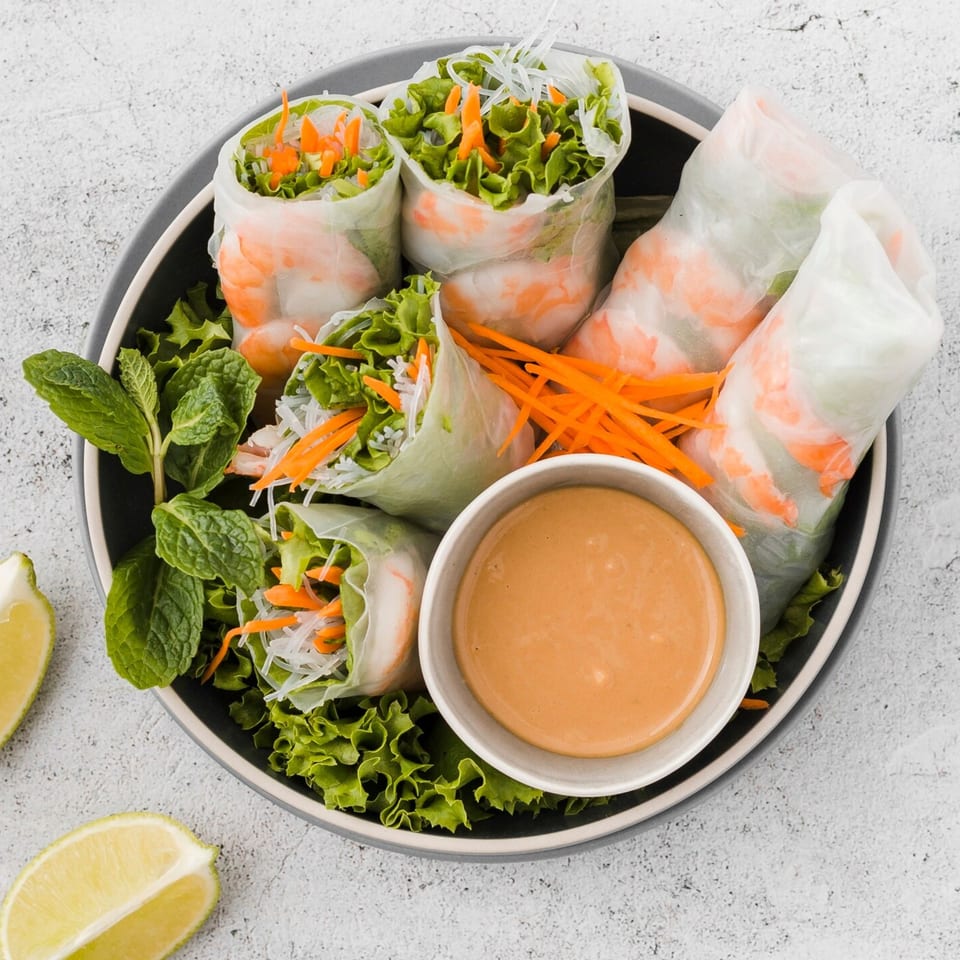 Vietnamese spring rolls with shrimp, lettuce, carrots, and vermicelli, served with peanut sauce.
